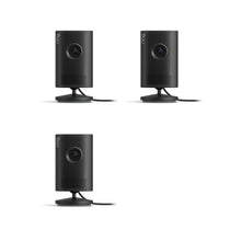  Plug-In / Black / 3-pack:Indoor Cam Plus. Three black, cylindrical Indoor Cam Plus. Two devices are standing on a small circular base.