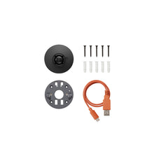 Black camera mount with grey mounting plate, screws and anchors, and an orange USB-A to micro-USB cable arranged on a white background.