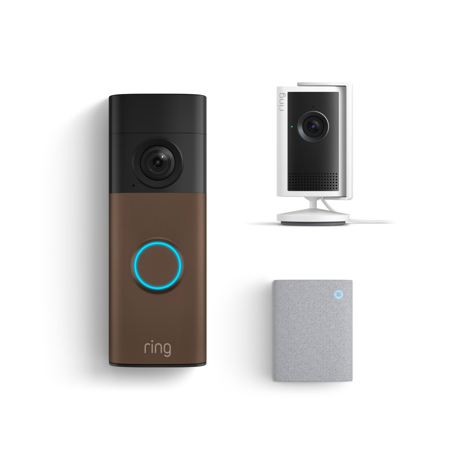 Ring smart home kit: bronze video doorbell with blue-lit button, white indoor camera on stand, and small gray chime.