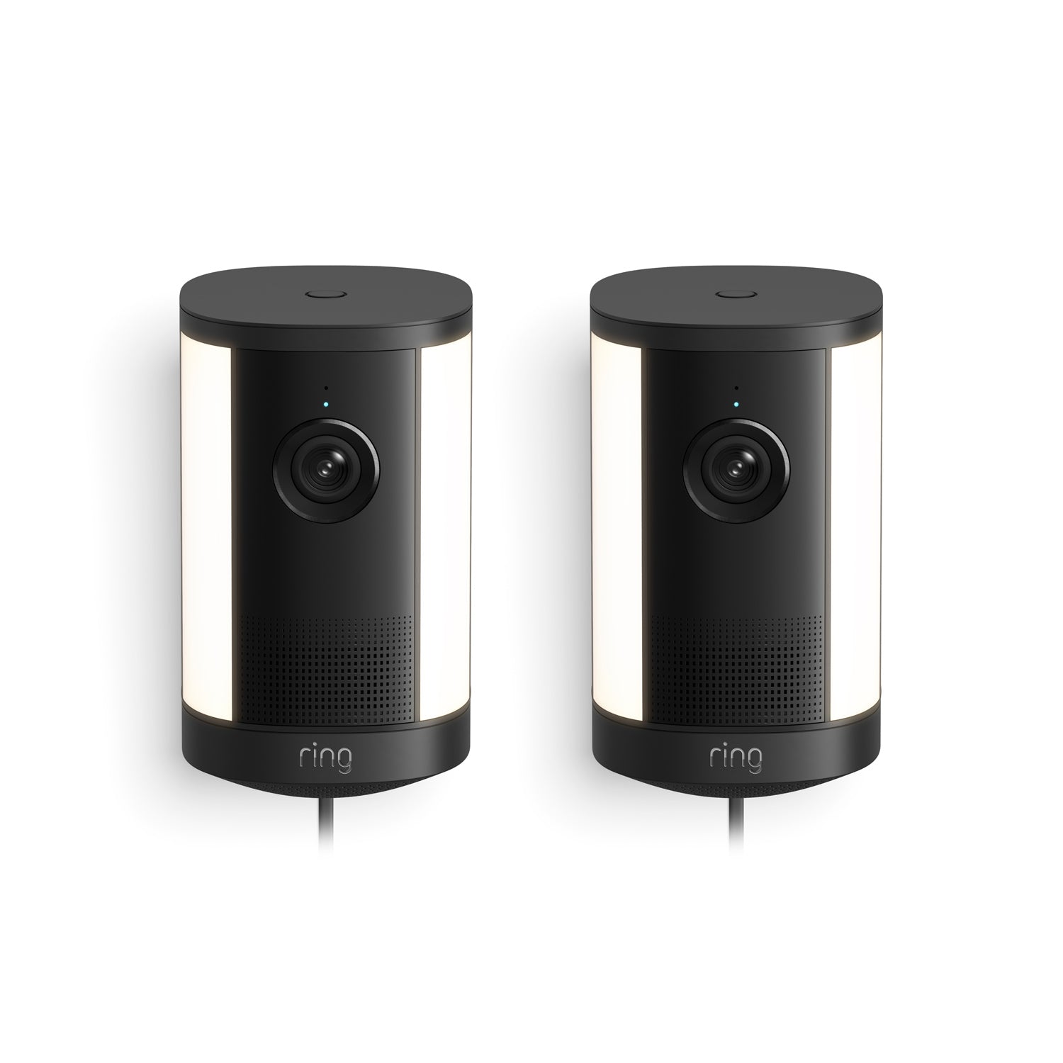 Pair of black Ring spotlight security cameras with integrated white side lights, front lenses, and cords, shown against a white background.