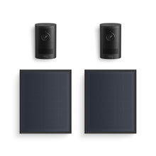 Two black Ring indoor/outdoor cameras paired with two rectangular solar panels on a white background.
