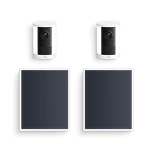 Two white Ring spotlight Cam units with built-in lights shown above two black rectangular solar panels on a white background.