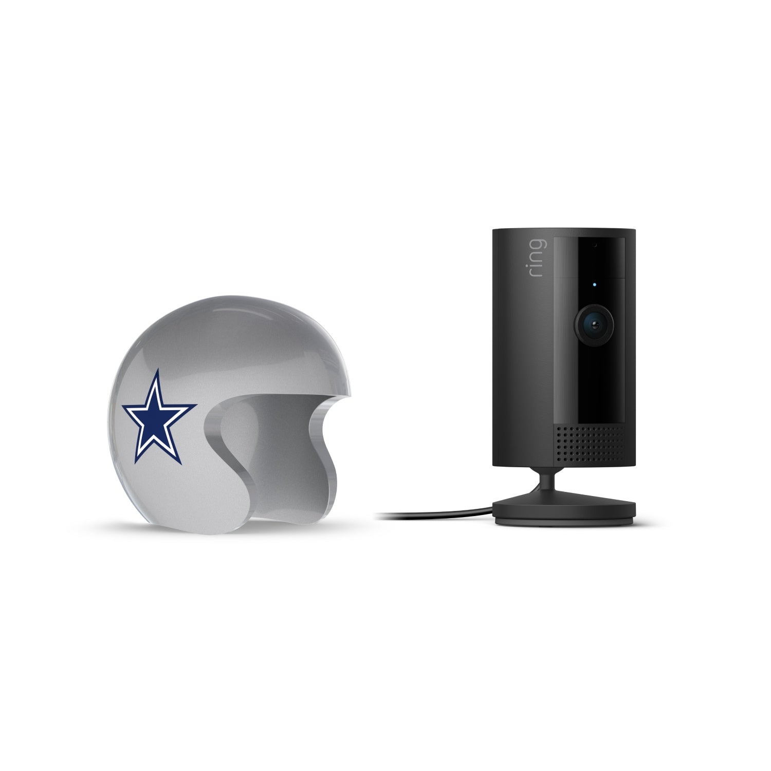 Black Ring indoor camera on a stand next to a silver football helmet with a blue star logo, against a white background.