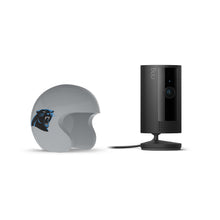 Black Ring indoor camera on a stand beside a gray mini football helmet with a black-and-blue panther logo, on a white background.