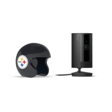 Black Ring indoor camera on a stand next to a glossy black mini football helmet with a Steelers logo, set against a white background.