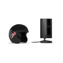 Black Ring indoor camera on a stand beside a glossy black mini football helmet with the Houston Texans logo on a white background.