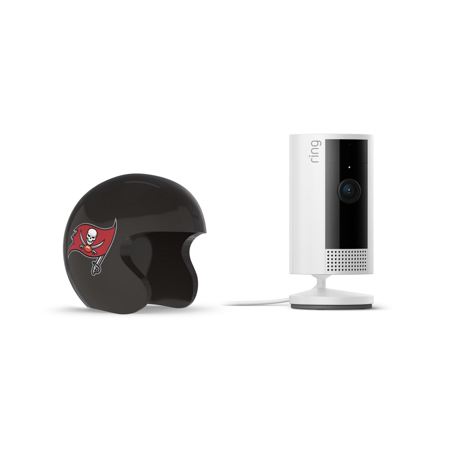 Black mini football helmet with red pirate flag logo next to a white Ring indoor security camera on a stand with power cord.
