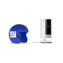 Blue NY football mini helmet beside a white Ring indoor camera on a stand with power cord, set against a white background.