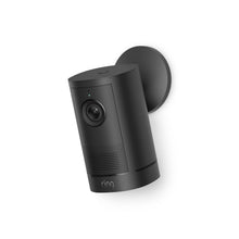 Black Ring Outdoor security camera mounted on a wall, angled left, with lens, status light, and speaker grille visible.