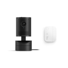 Black Pan-tilt indoor security camera on a base with power cord, shown beside a small white Ring-branded wireless module.