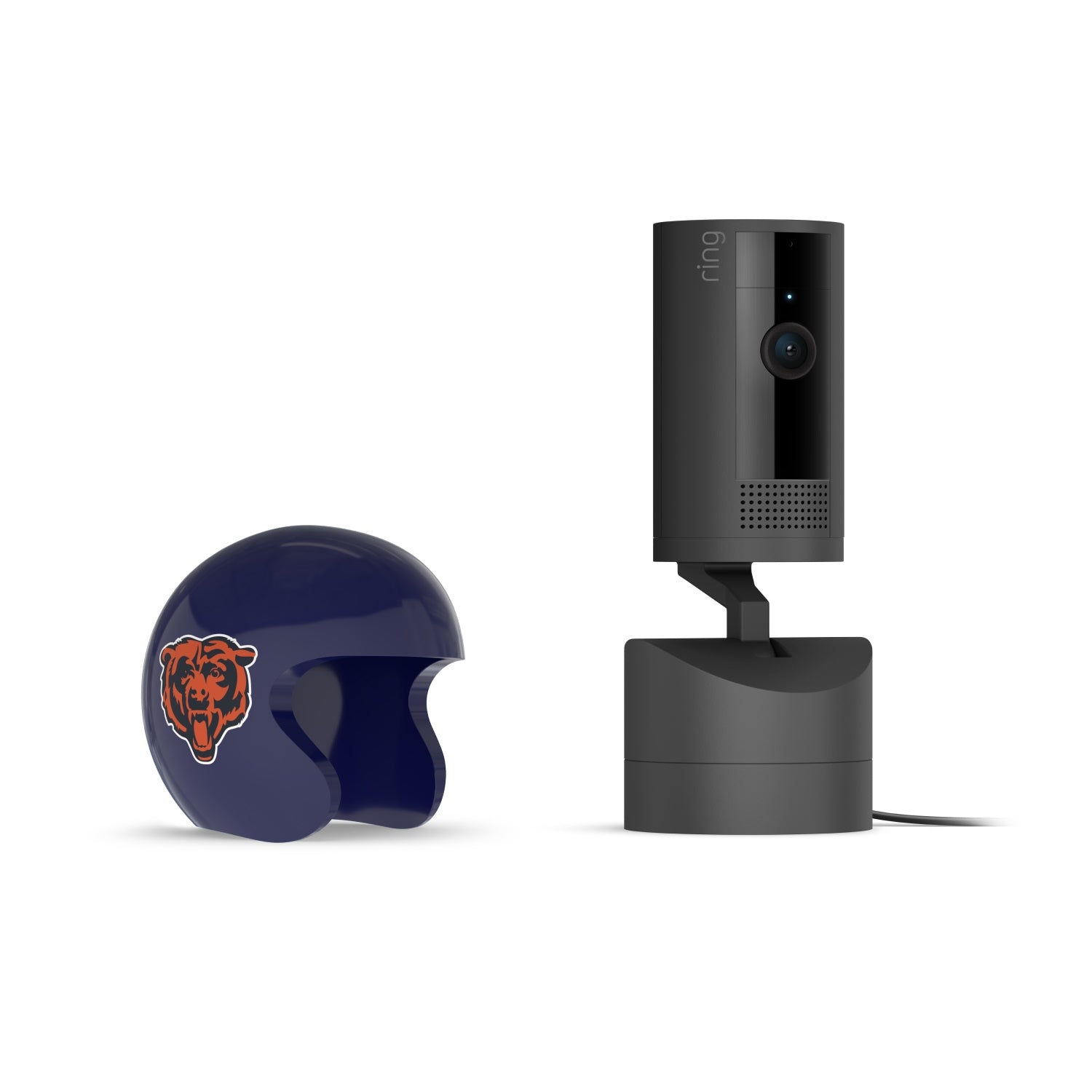 Black Ring indoor camera on a base beside a glossy navy mini football helmet with an orange bear logo on a white background.