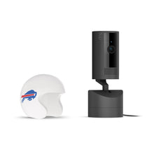 Black Ring indoor camera on a stand next to a white mini football helmet with a blue buffalo logo on a plain white background.