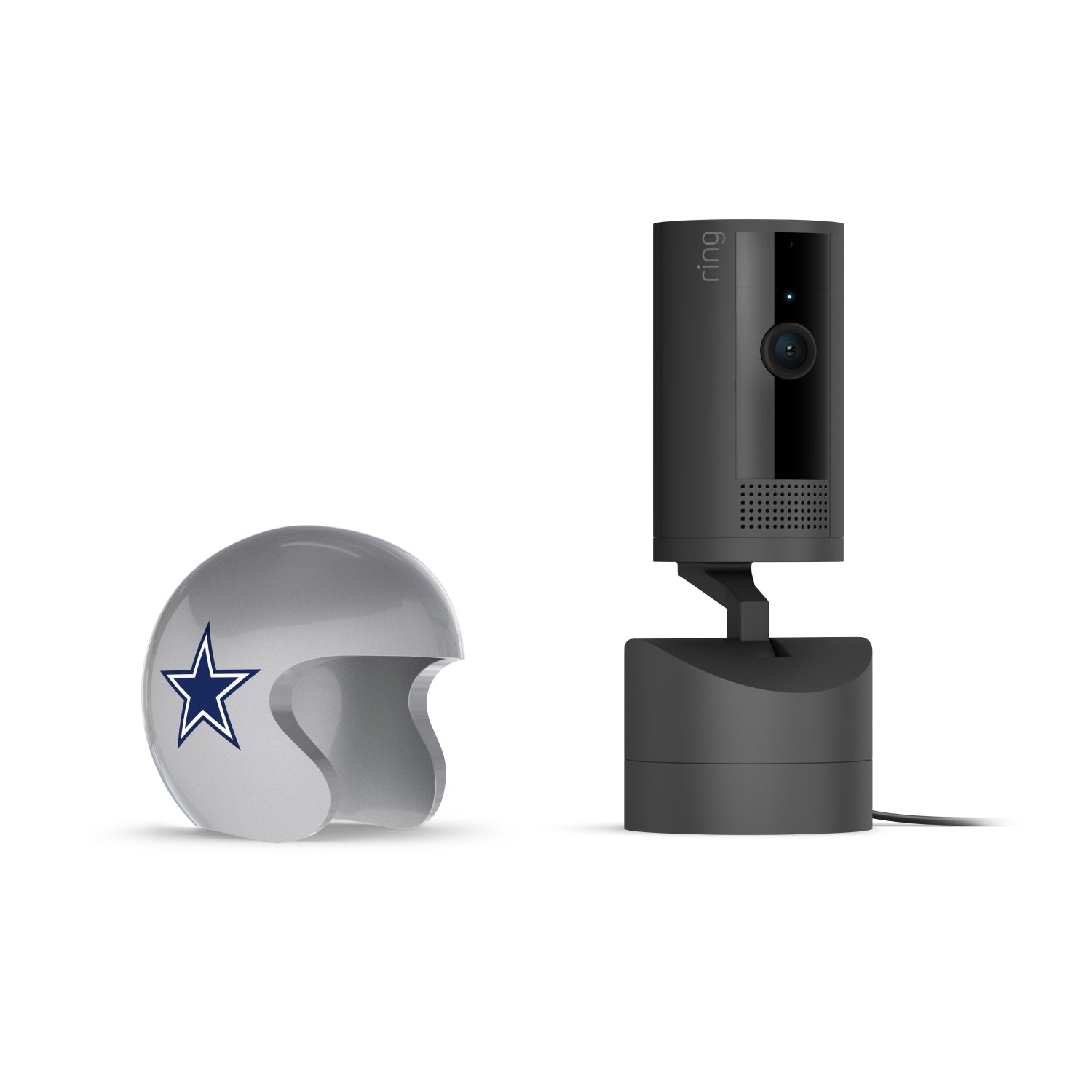 Black Ring indoor camera on a stand next to a silver mini helmet with a blue star logo, against a white background.