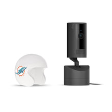 Black Ring indoor camera on a stand next to a white mini football helmet with a teal dolphin logo on a white background.
