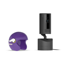 Black Ring indoor camera on stand beside a small purple Vikings football helmet on a white background.