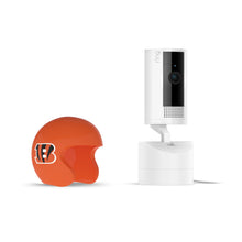 White Ring Pan-Tilt indoor camera on a stand beside an orange mini football helmet with a black-and-orange “B” logo, on a white background.
