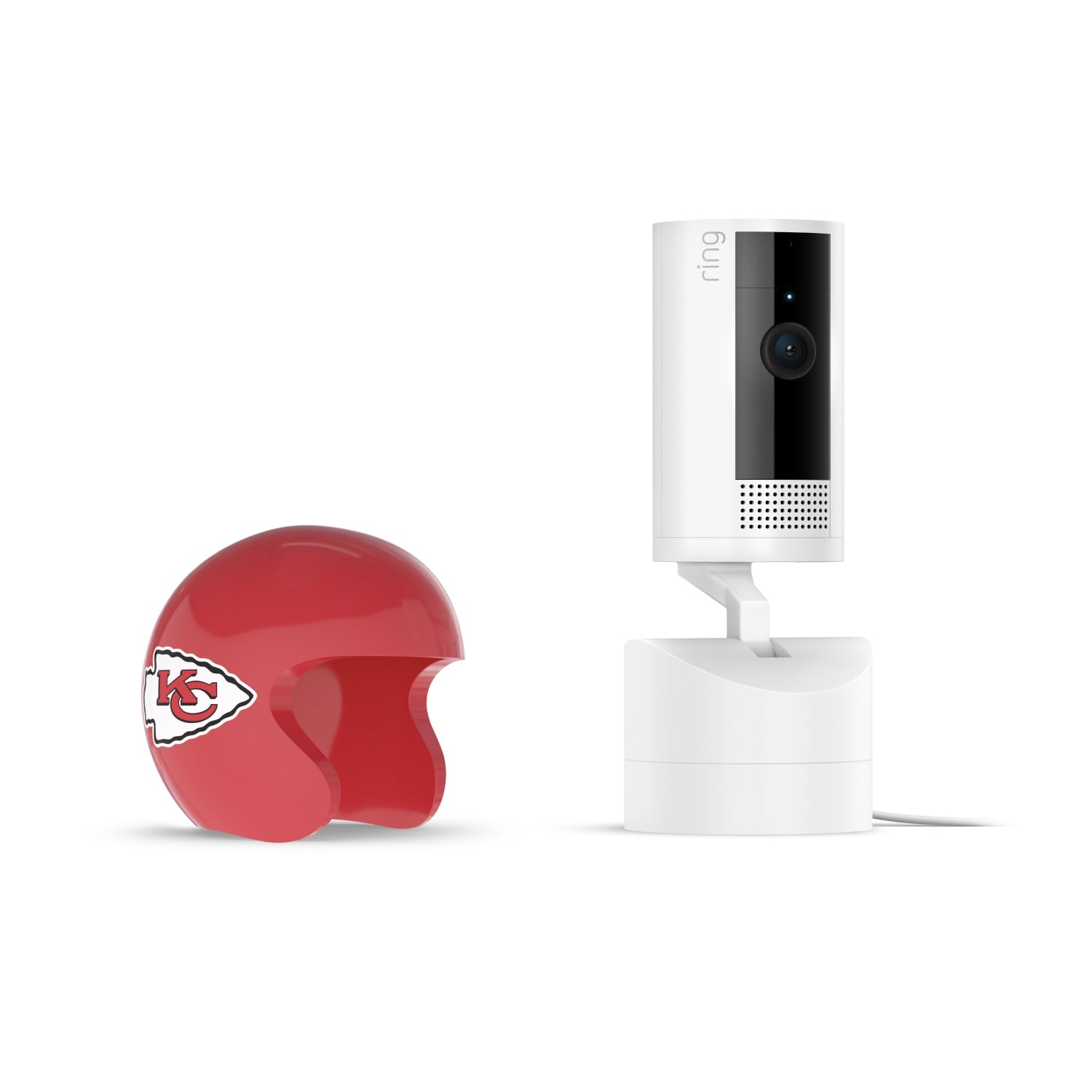 White Ring Pan-tilt indoor camera on a stand next to a small red Kansas City Chiefs helmet on a white background.