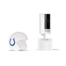 White Pan-tilt indoor camera on a charging dock beside a white football helmet with a blue horseshoe logo, set on a white background.