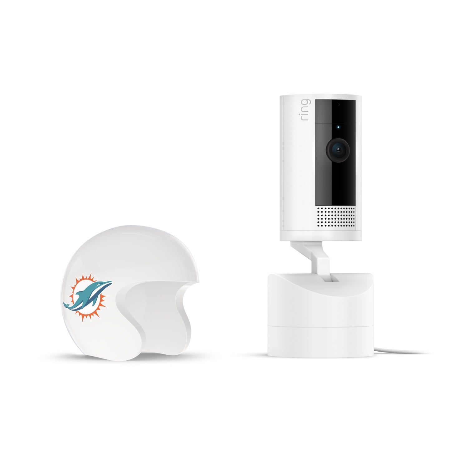 White Ring indoor camera on stand next to a white mini football helmet with a teal dolphin logo on a plain white background.