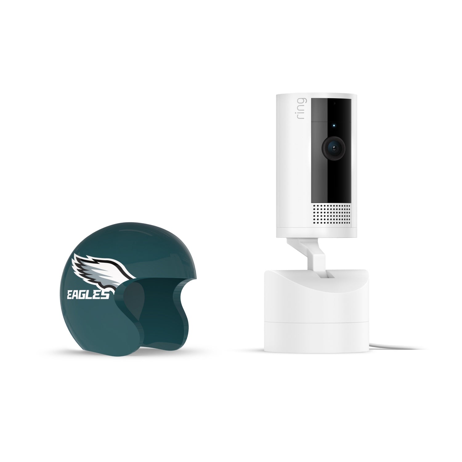 White Ring indoor camera on stand next to a dark green mini helmet cover with an Eagles logo, on a white background.