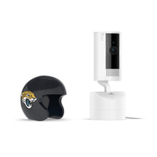 White Ring Pan-tilt indoor camera on a base next to a black mini football helmet with a jaguar logo on white background.