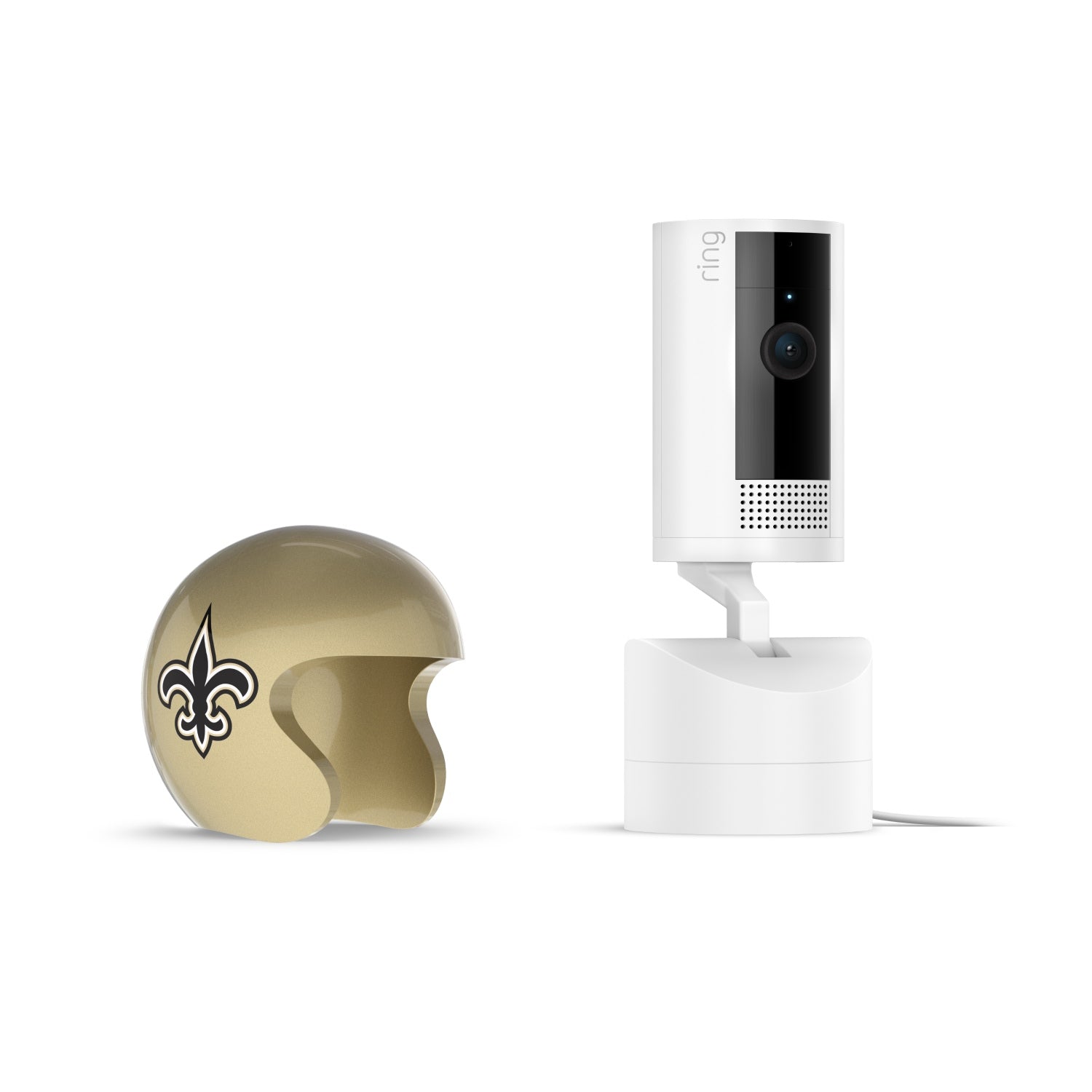 White Ring indoor camera on a stand next to a small gold helmet with a black fleur-de-lis logo on a white background.