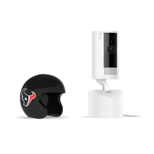 Black mini football helmet with Houston Texans logo beside a white Ring Pan-Tilt indoor camera on a stand against a plain white background.