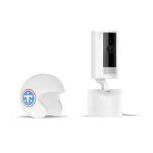 White Ring indoor camera on a stand next to a small white helmet with a blue T logo and stars, both on a clean white background.