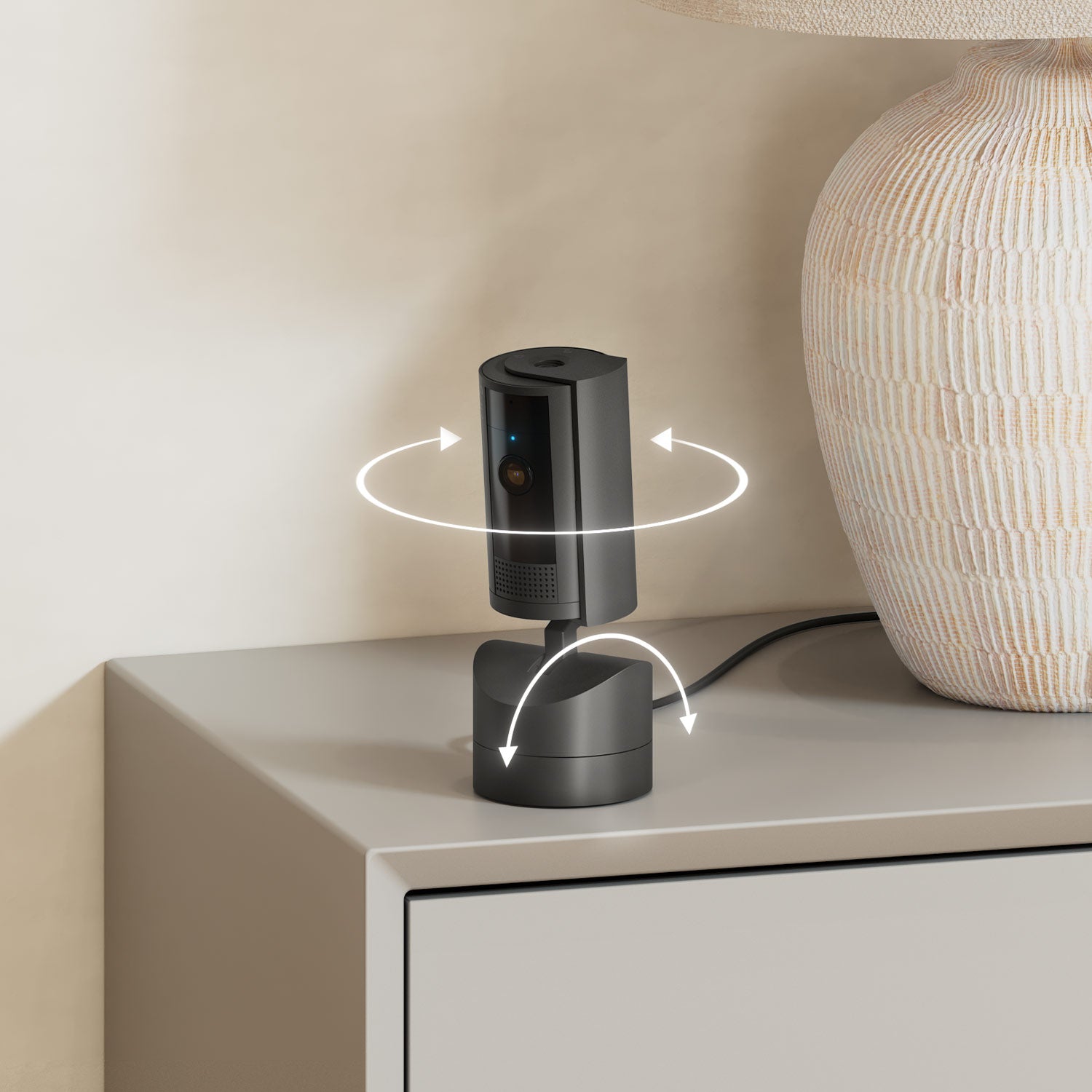 Black Ring Pan-Tilt Indoor Cam on table next to lamp, with arrows indicating 360-degree rotation and tilt-adjustment.