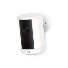 White Ring outdoor camera with black lens panel, side LED light strips, and speaker grille, mounted on a wall bracket.