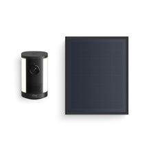 Black Ring floodlight camera with side LEDs next to a rectangular black solar panel on a white background.